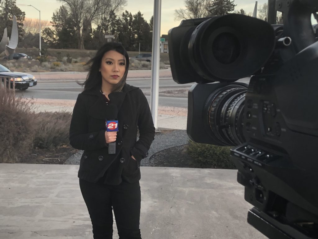 Rhea Panela standing in front of camera talking on a microphone